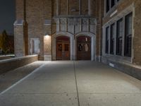 a street light is lit on a brick building near a sidewalk and a fire hydrant