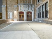 a street light is lit on a brick building near a sidewalk and a fire hydrant
