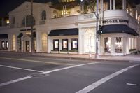 a building with lit lights on and street behind it that reads brooks brothers clothing company