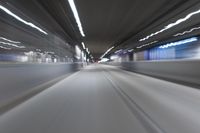 a blurry image of a train going through an indoor tunnel with light trails in the distance