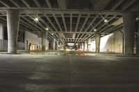 the car is driving underneath the overpass under the bridge at night, leaving its shadow