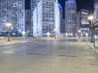 a black paved street in a big city at night and buildings on either side of it