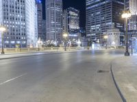 a black paved street in a big city at night and buildings on either side of it