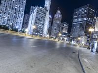 a black paved street in a big city at night and buildings on either side of it