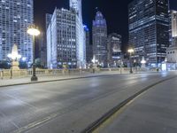 a black paved street in a big city at night and buildings on either side of it