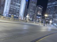 a black paved street in a big city at night and buildings on either side of it