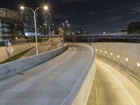 highway overpass with traffic at night, with buildings and street lights in background, with street lights on, street lamps to left