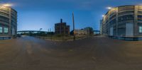 fisheye lens view showing an empty street and two large buildings at night with no traffic