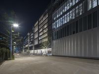 an empty parking lot with a lamp on the street and other buildings lit up at night