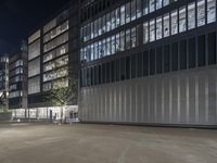 an empty parking lot with a lamp on the street and other buildings lit up at night