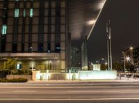 a view of a city intersection at night time, with a street light on a walkway beside the building