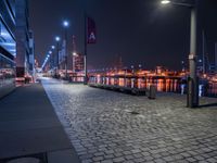 the street lights are on, near the water and in a city by night with the sky