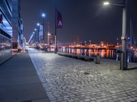 the street lights are on, near the water and in a city by night with the sky