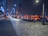 the street lights are on, near the water and in a city by night with the sky