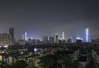 the view from the top of a high rise building, of the city lit up at night