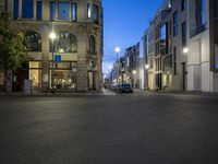 a city street that has parked cars on it at night as cars wait for traffic