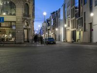 a city street that has parked cars on it at night as cars wait for traffic