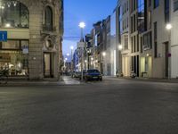 a city street that has parked cars on it at night as cars wait for traffic