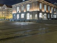 an intersection with two trains and building in the background at night time in copenhagen, denmark