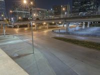 a street view at night of a city intersection with several cars parked under a bridge