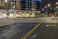 an empty street with stores and lights at night time outside of a building in downtown