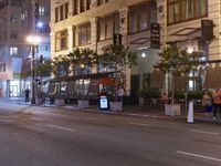 an empty street with stores and lights at night time outside of a building in downtown