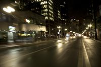 the lights are shining brightly on a busy city street in the night time, blurred with cars