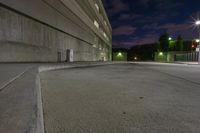 there is a street at night time, and in front is an empty parking garage with a ramp that is in the middle of it