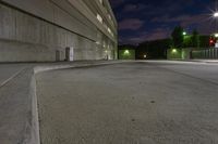 there is a street at night time, and in front is an empty parking garage with a ramp that is in the middle of it