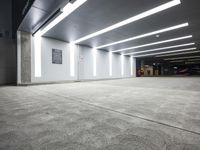 a empty parking lot with lights on from above and a wall on one of the floors