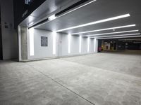 a empty parking lot with lights on from above and a wall on one of the floors