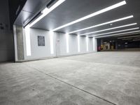 a empty parking lot with lights on from above and a wall on one of the floors