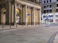 a empty plaza at night with the buildings in the background and many signs lit up