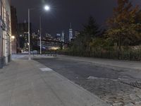 an empty sidewalk with no people walking or sitting in it at night on the sidewalk