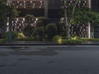 the empty street is next to an office building at night, with an asphalt road running past