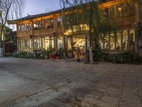 a group of people outside a large building with wooden buildings in the background at night