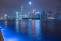 a city street with buildings and neon lights at night time in hong china as seen from an empty city highway