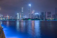 a city street with buildings and neon lights at night time in hong china as seen from an empty city highway