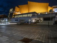 a building lit up in yellow by the dark sky at night with stairs going up to the back