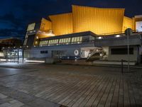 a building lit up in yellow by the dark sky at night with stairs going up to the back