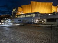 a building lit up in yellow by the dark sky at night with stairs going up to the back