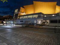 a building lit up in yellow by the dark sky at night with stairs going up to the back