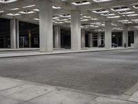 large open walkway leading up to a parking structure at night with lots of square tiles and poles at the bottom