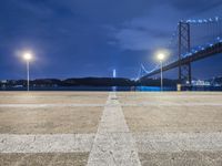 a large bridge over the ocean with street lights on it at night with bright lights on the ground