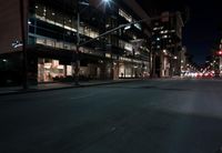 a view from the front seat of a car on a city street at night with lights shining and buildings in the background