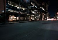 a view from the front seat of a car on a city street at night with lights shining and buildings in the background