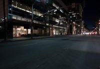a view from the front seat of a car on a city street at night with lights shining and buildings in the background