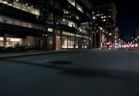 a view from the front seat of a car on a city street at night with lights shining and buildings in the background