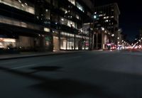 a view from the front seat of a car on a city street at night with lights shining and buildings in the background