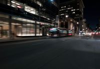 a view from the front seat of a car on a city street at night with lights shining and buildings in the background
